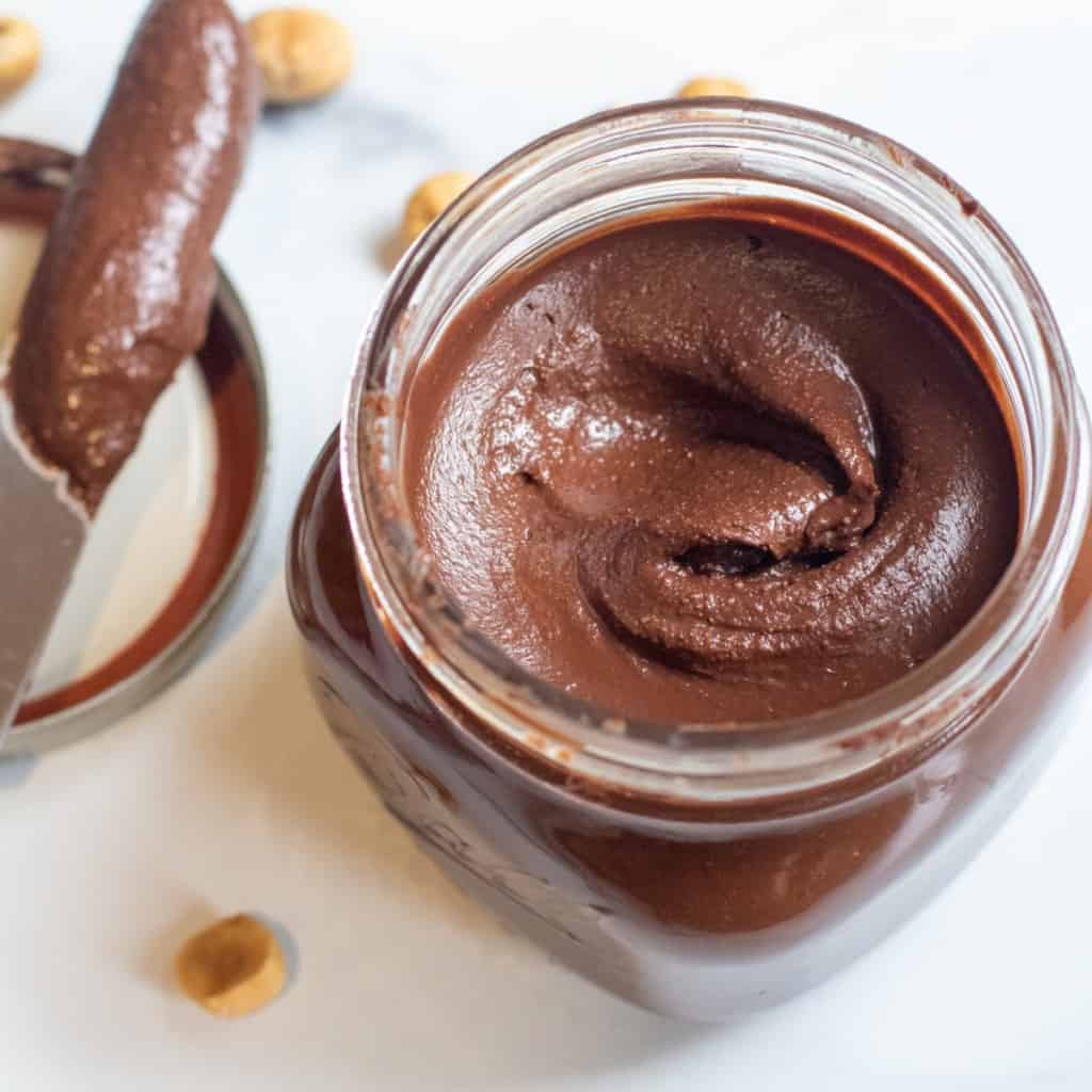 an open jar of nutella with a knife in it.