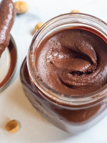 an open jar of nutella with a knife in it.