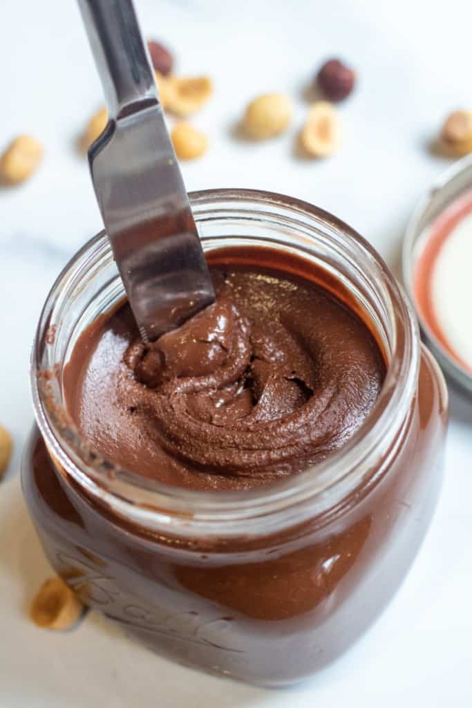 an open jar of nutella with a knife in it.