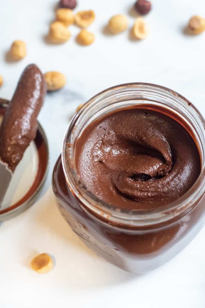 an open jar of nutella with a knife in it.