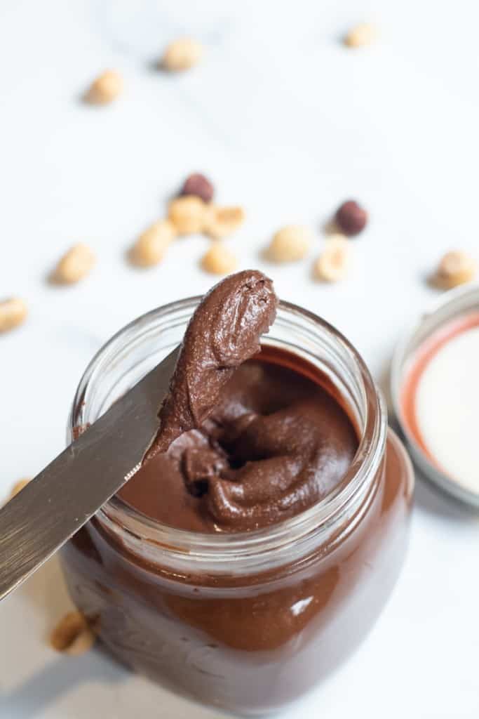 an open jar of nutella with a knife in it.