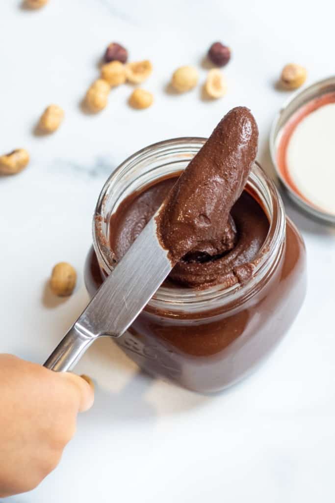 an open jar of nutella with a knife in it.