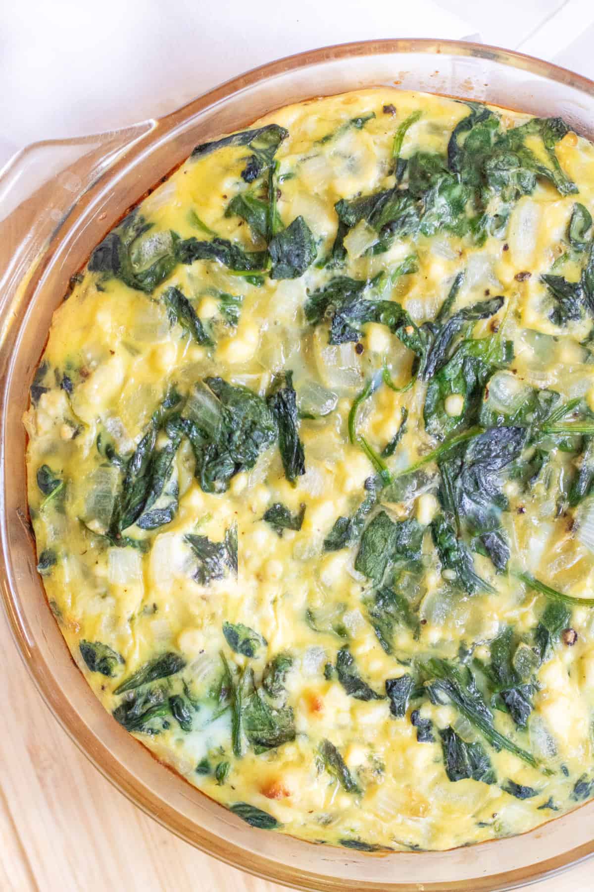 overhead of a crustless quiche with spinach and eggs.