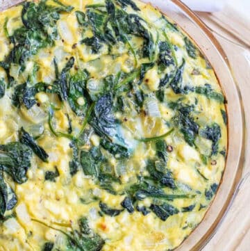 overhead of a crustless quiche with spinach and eggs.