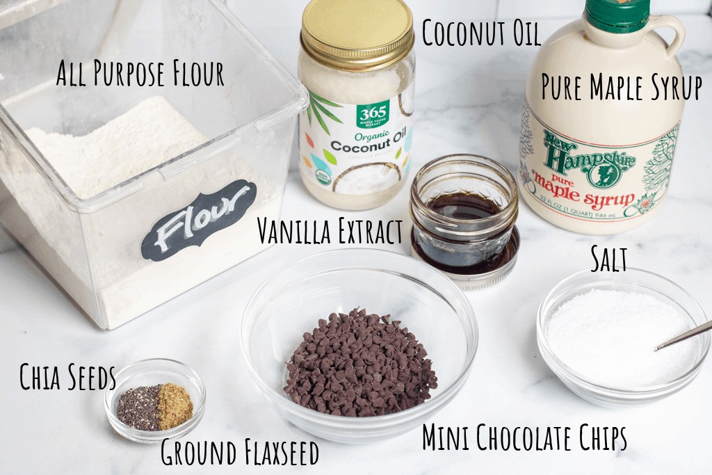 flour, coconut oil, maple syrup, chocolate chips, vanilla extract, salt, and seeds in a bowl labeled on counter.