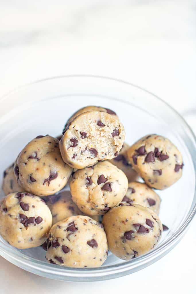 a bowl of cookie dough balls with one with a bite taken out.