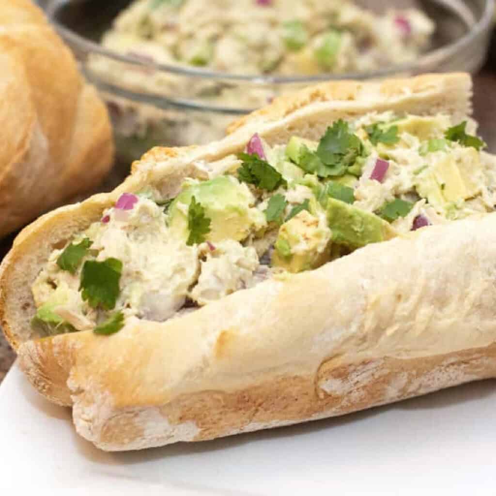 a sub with tuna salad with avocado on a plate.