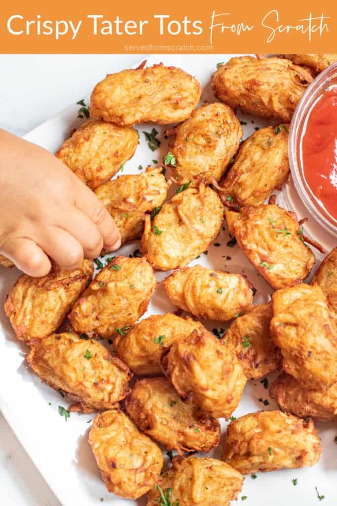 a plate of homemade tater tots with ketchup and a little hand grabbing one with Pinterest pin text..