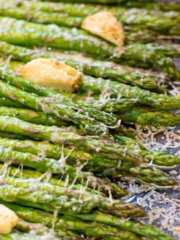 a pan of cooked asparagus with garlic and melted cheese.