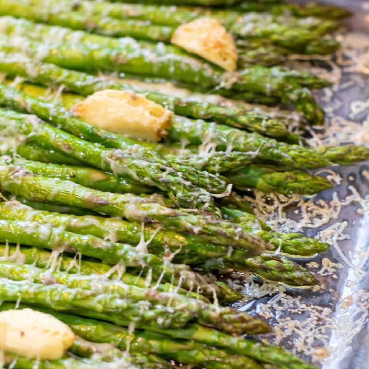 a pan of cooked asparagus with garlic and melted cheese.