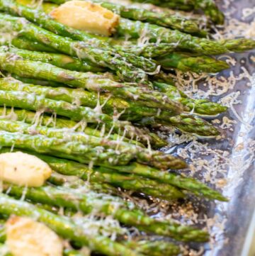 a pan of cooked asparagus with garlic and melted cheese.