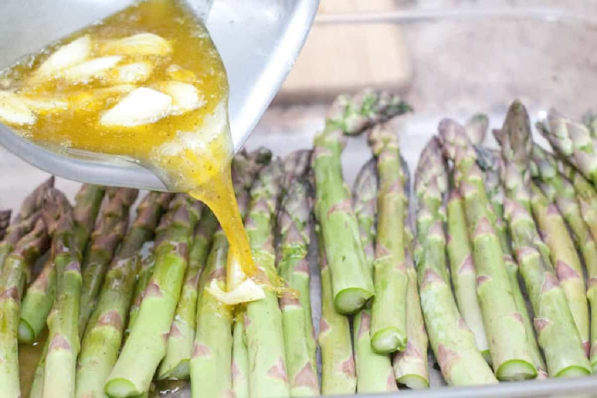 garlic oil being poured on asparagus.