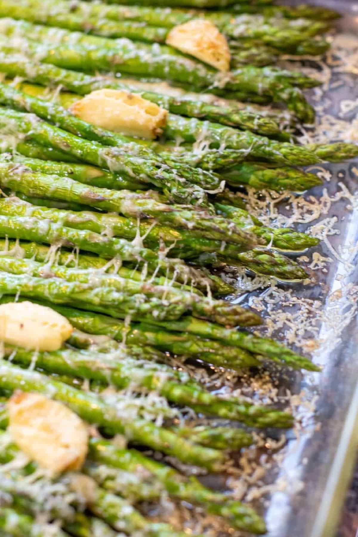 a pan of cooked asparagus with garlic and melted cheese.