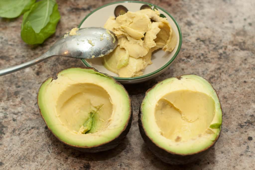 a halved avocado with some scooped out with a spoon.