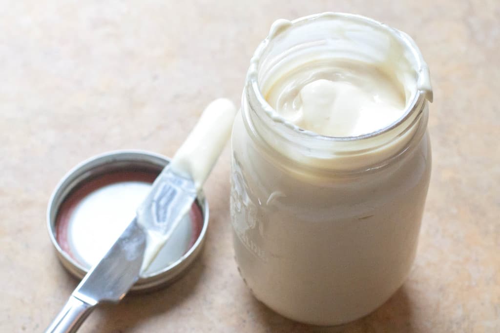 homemade mayonnaise from scratch in a mason jar with knife on lid.