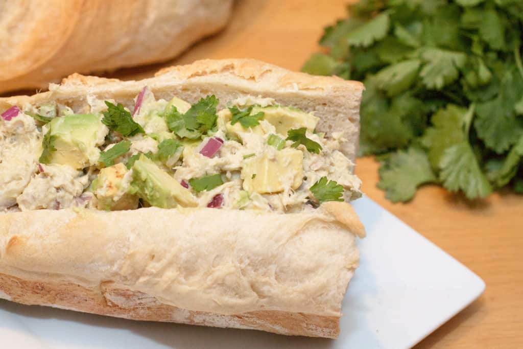 a sub filled with tuna salad and avocado topped with cilantro