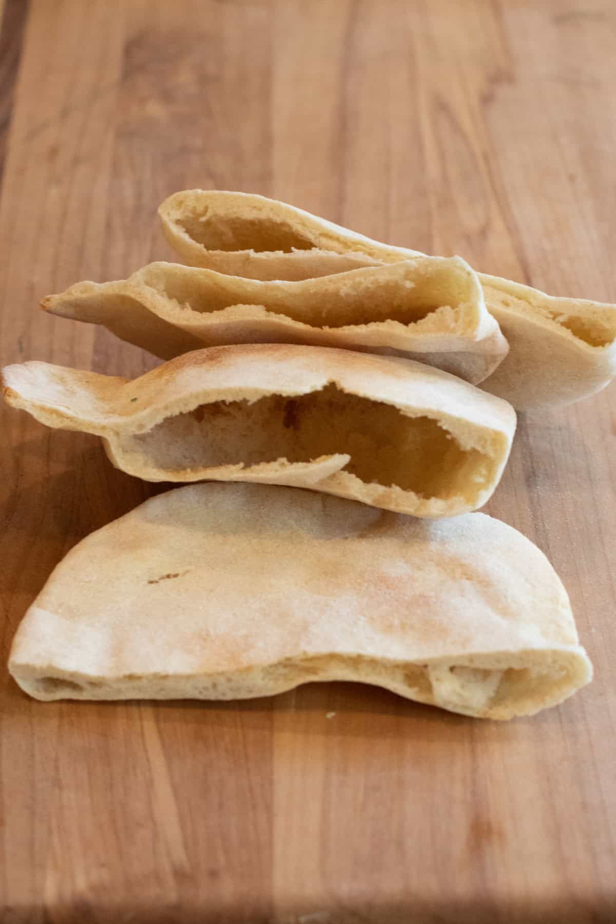 pita breads sliced in half on a cutting board.
