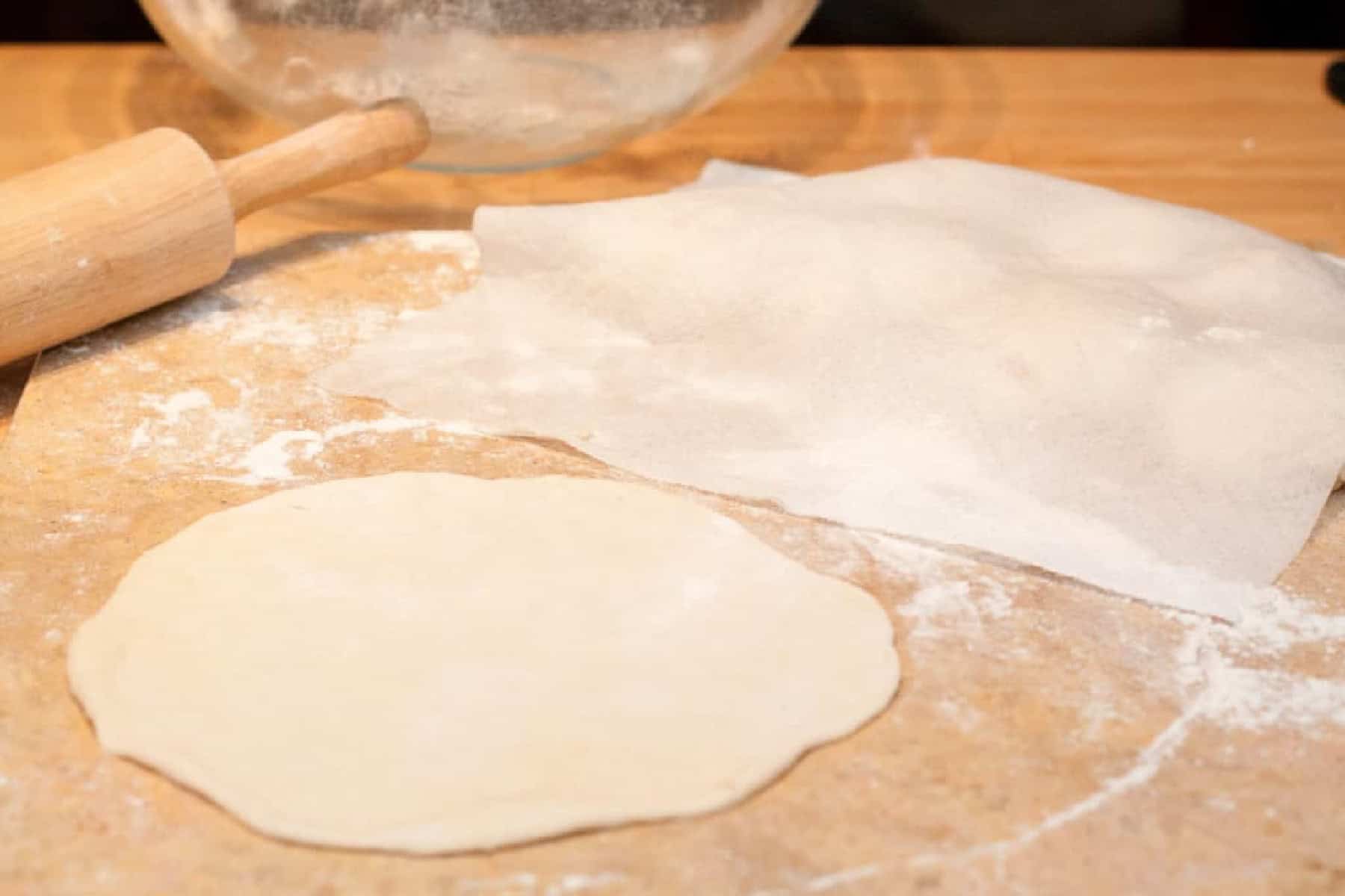 a rolled our thin round of dough on a cutting board and then other doughs under a wet paper towel.