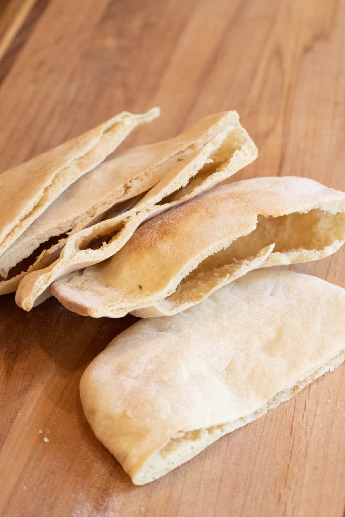 pita breads sliced in half on a cutting board.