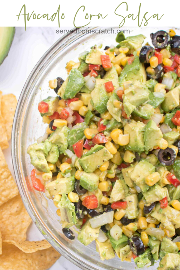 a large bowl of avocado salsa with olive, peppers, and corn and Pinterest pin text.