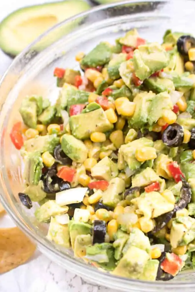 a large bowl of avocado salsa with olive, peppers, and corn.