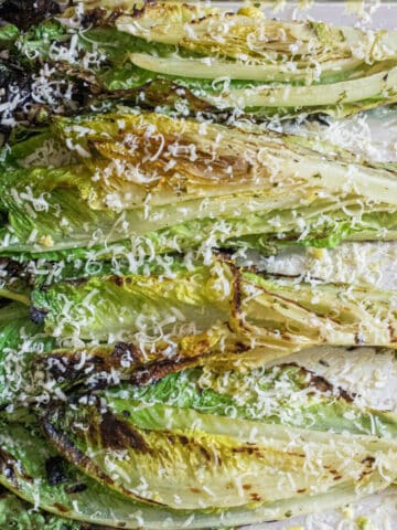 grilled romaine on a tray with Parmesan cheese.