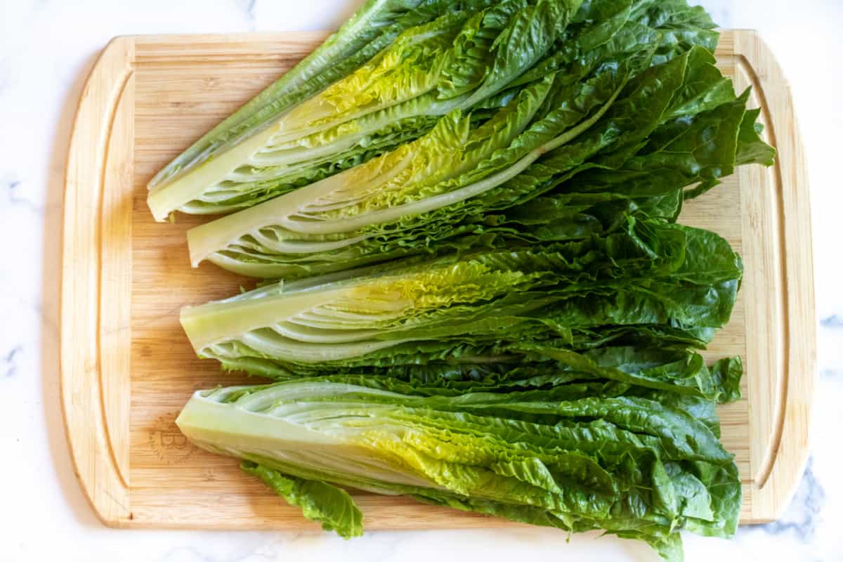 romaine cut in fourths on a cutting board.