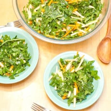 a large bowl of kale salad with two smaller bowls.