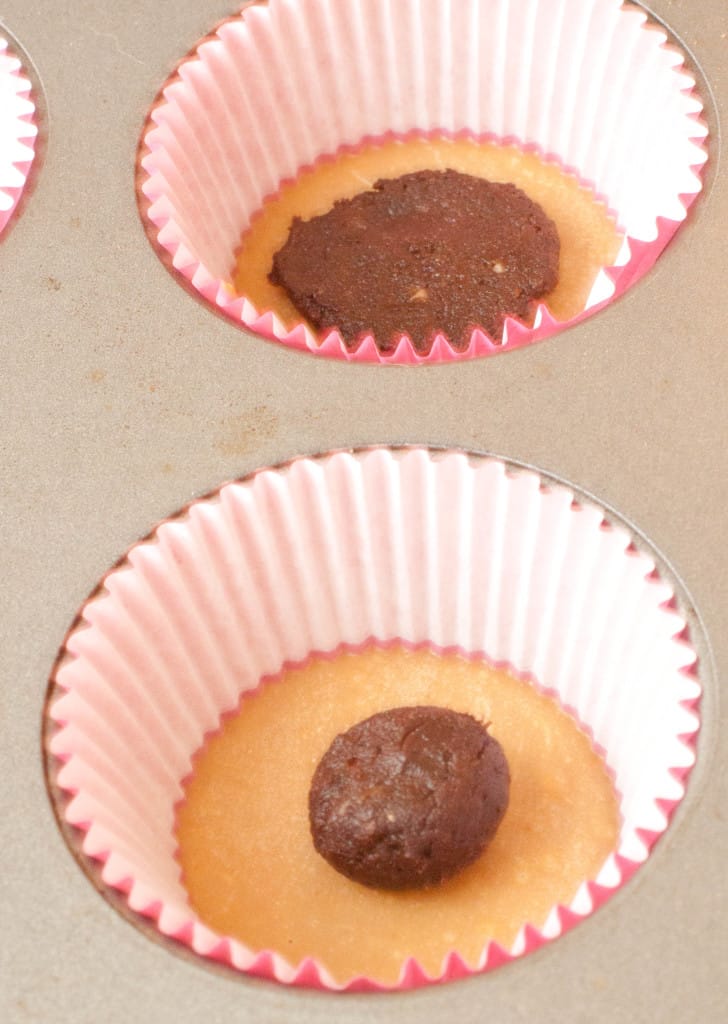 close up of muffin tin and liner with peanut butter and a ball of chocolate