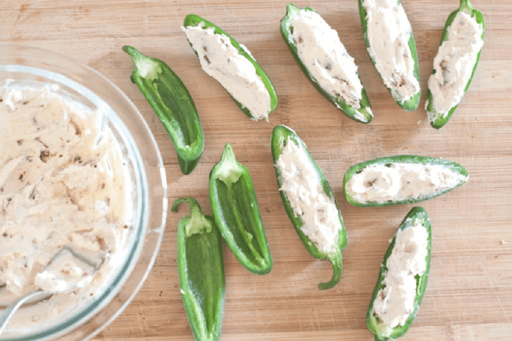 cheese stuffed jalapenos on a cutting board.