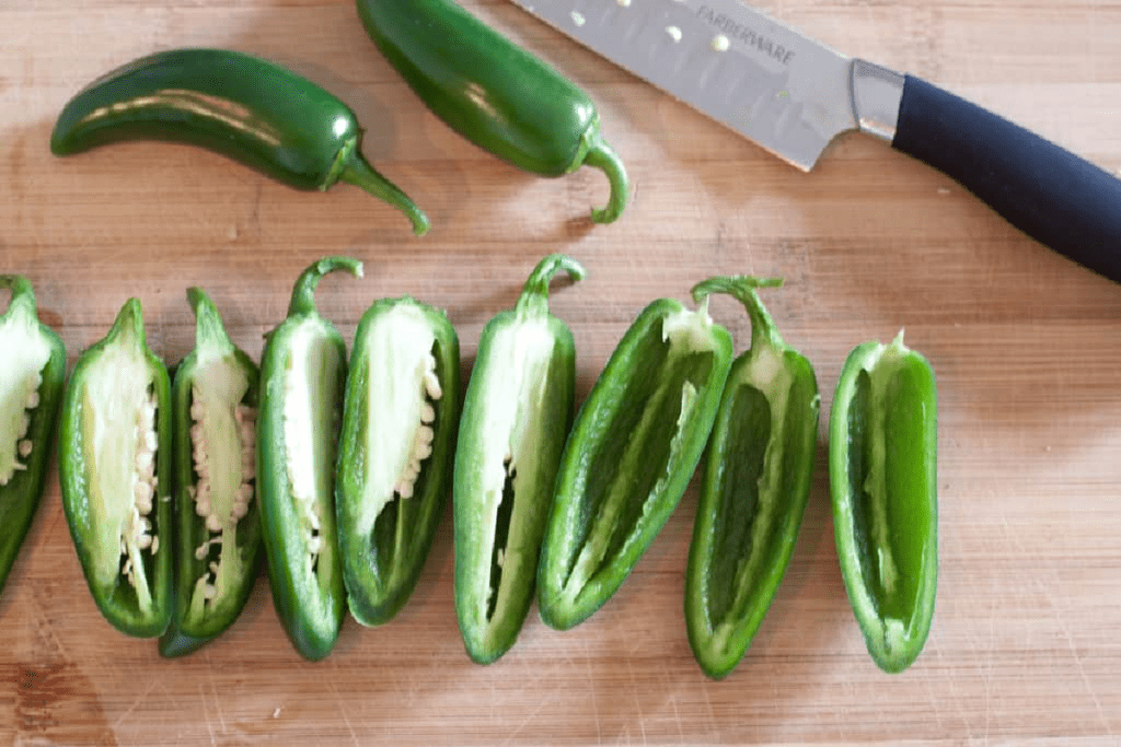 halved jalapenos on a cutting board with some deseeded.