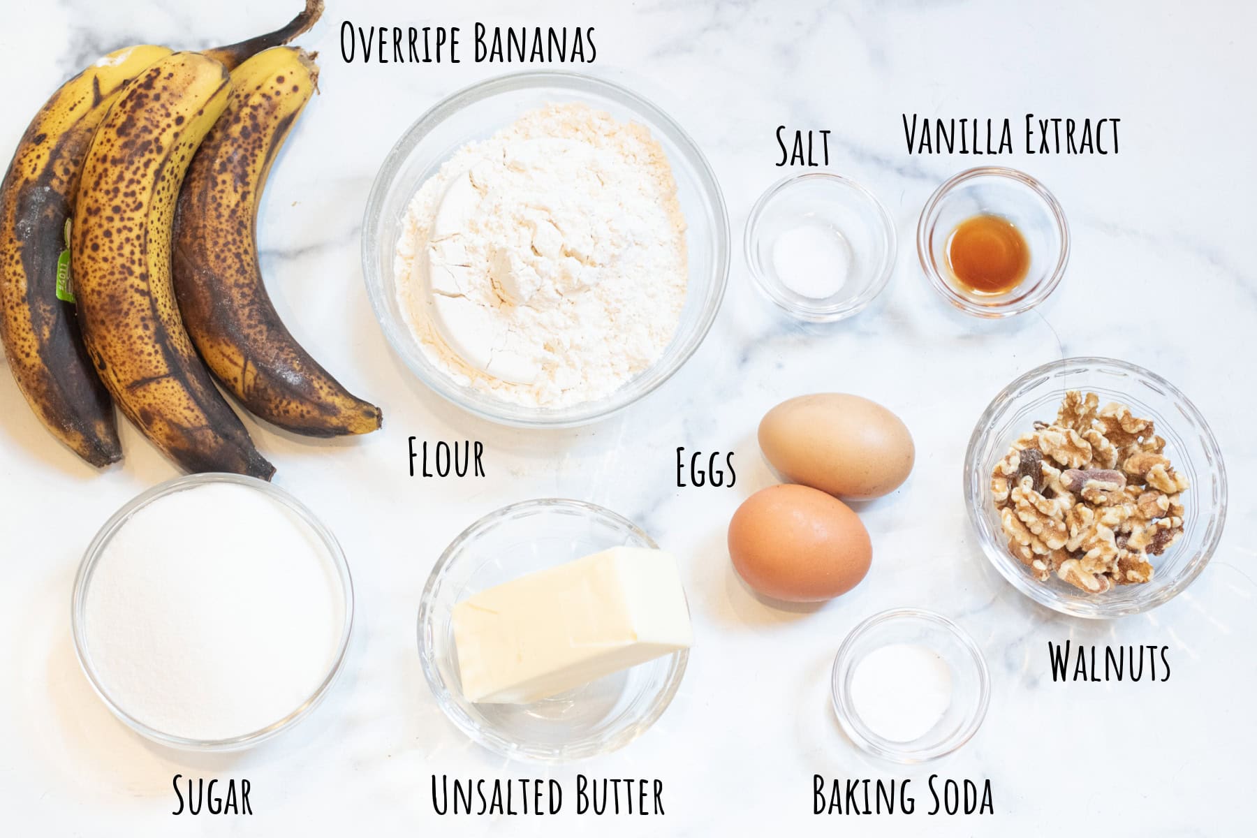 brown bananas, bowl of flour, bowls of extract, salt, baking soda, sugar, butter, eggs, and walnuts all labeled.
