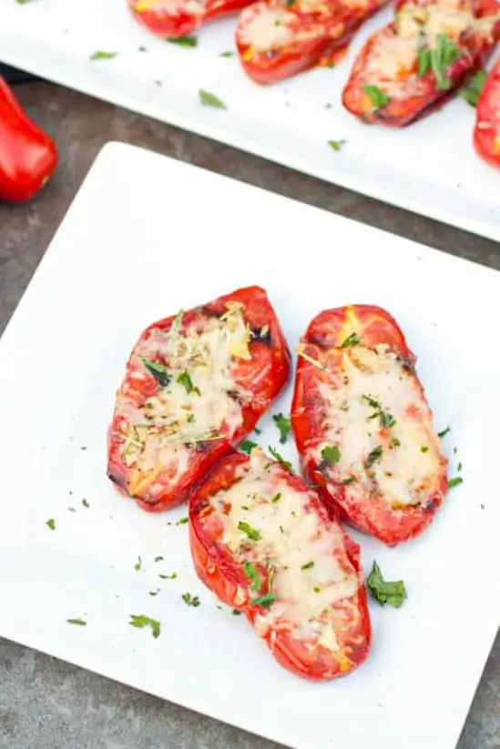a plate of halved tomatoes with melted cheese on a plate.