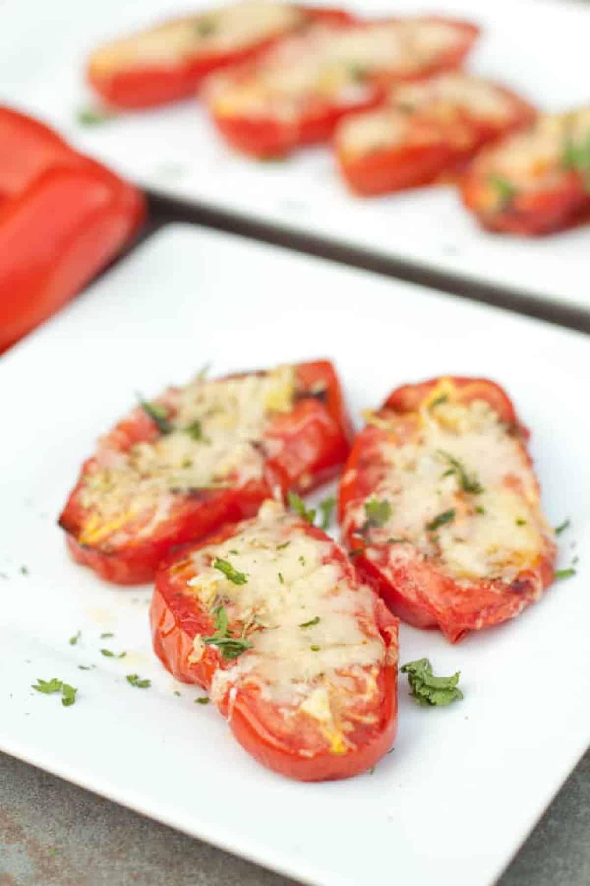 a plate of halved grilled tomatoes with melted cheese.