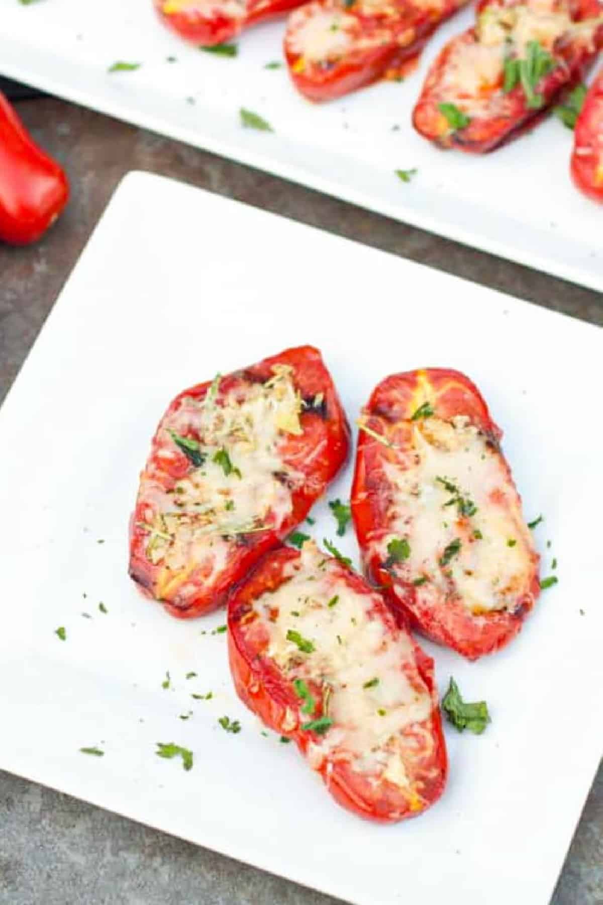 a plate of halved grilled tomatoes with melted cheese.