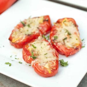 a plate of halved grilled tomatoes with melted cheese.