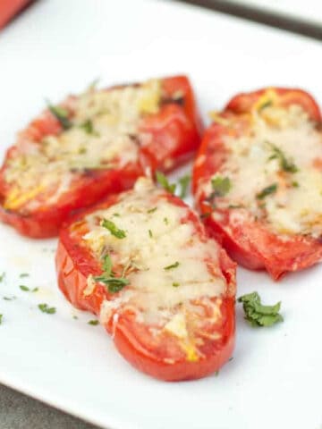 a plate of halved grilled tomatoes with melted cheese.