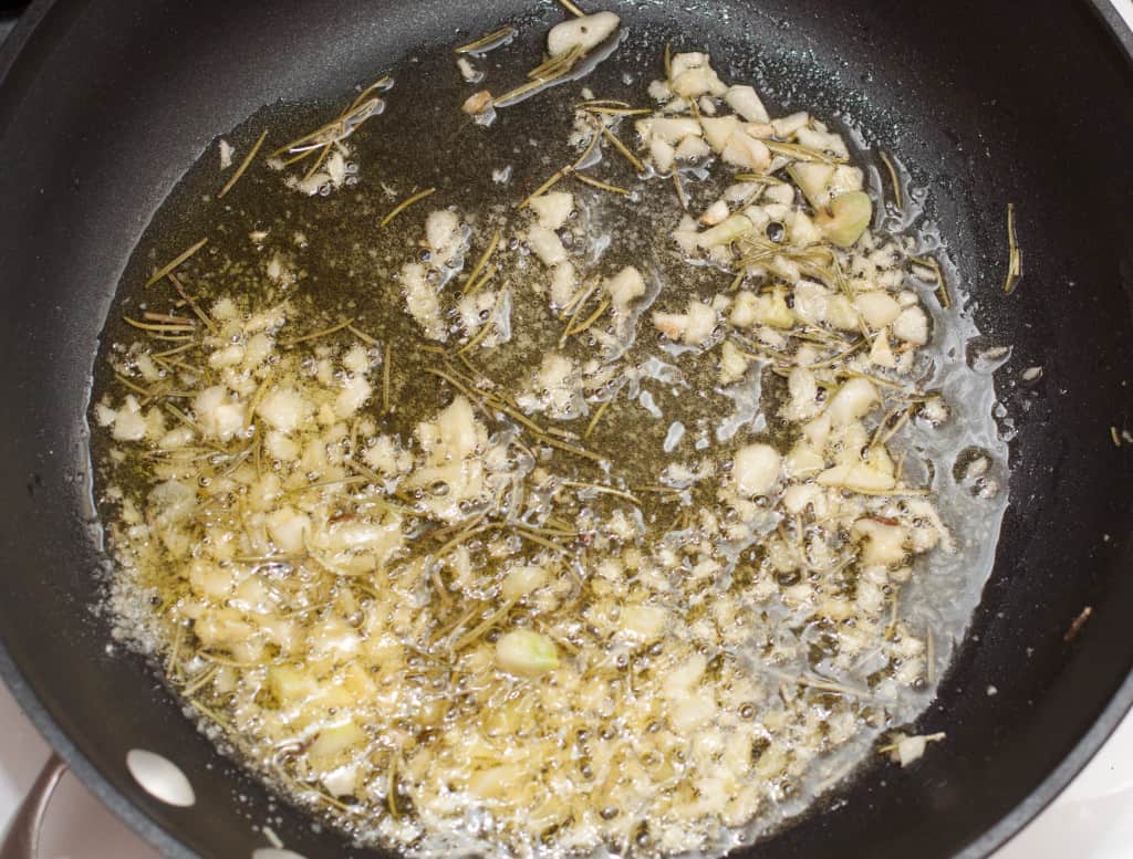 a pan with garlic and oil and rosemary.