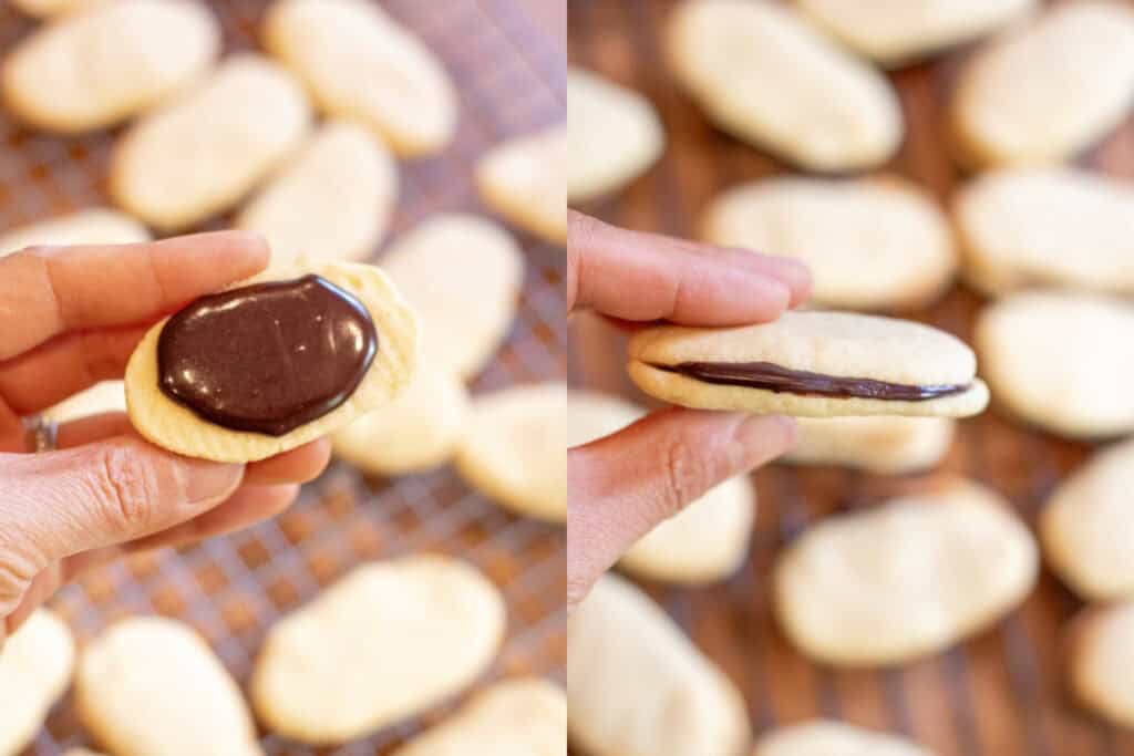 a hand holding a baked cookie with melted chocolate and then it sandwiched.