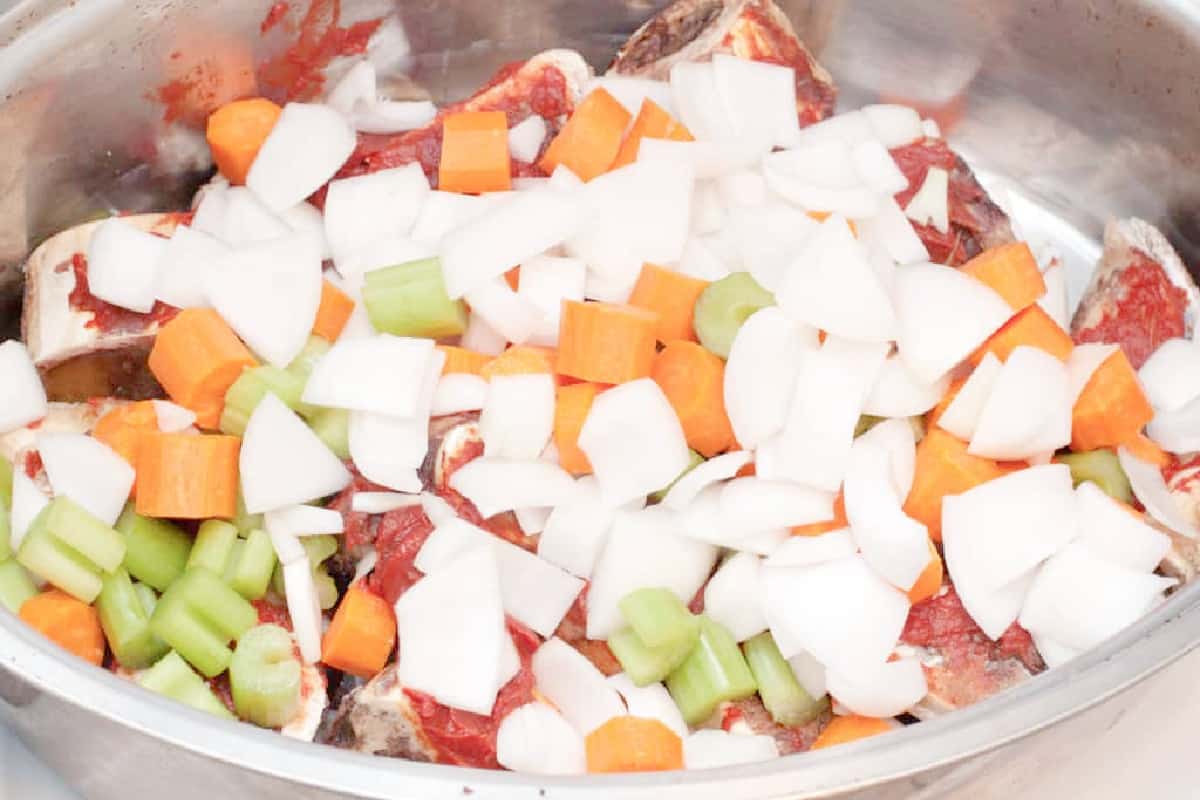 veggies covering tomato paste covered beef bones.