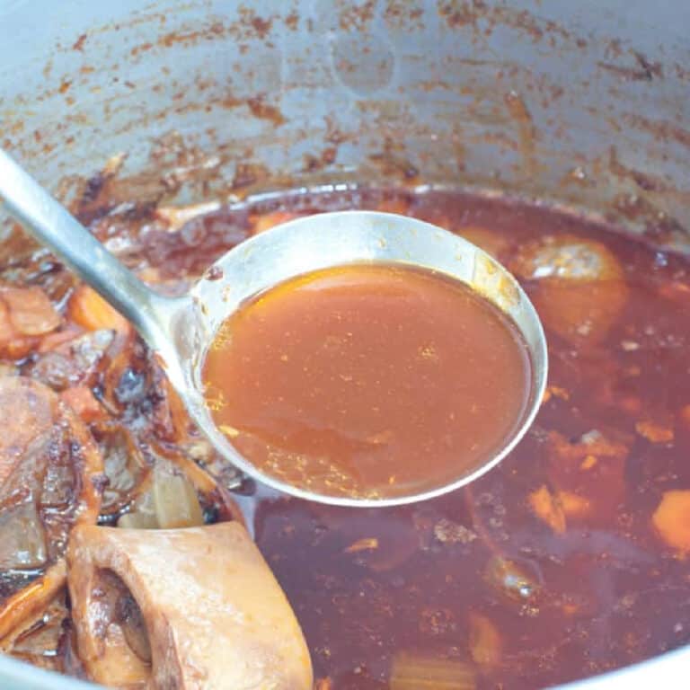 a ladle of beef stock over a pot.