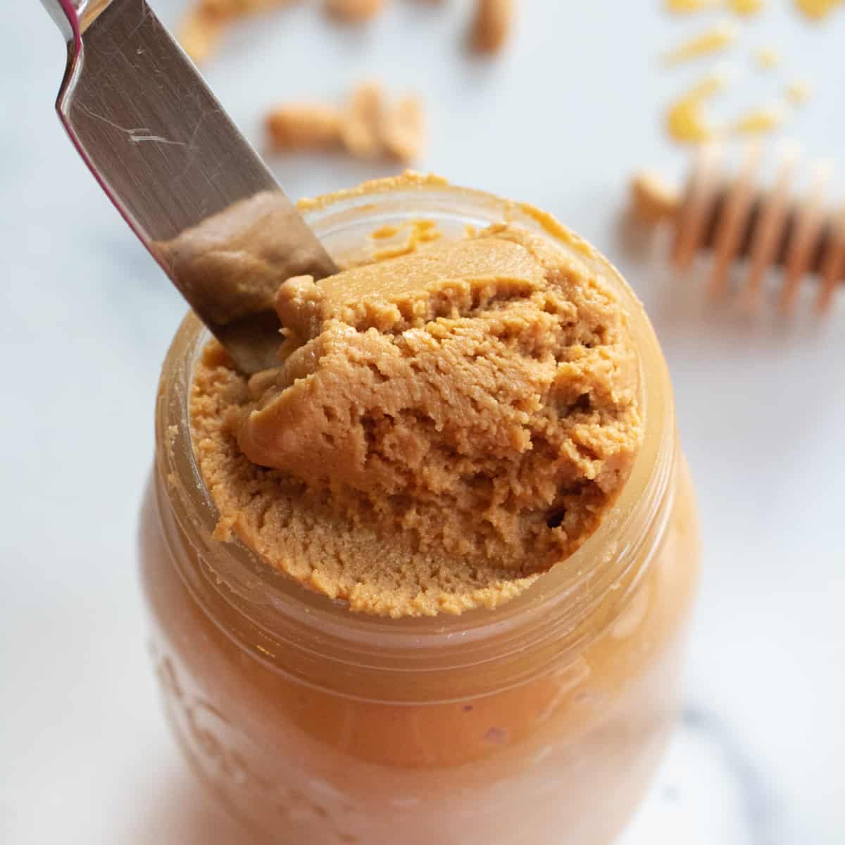 an open jar of peanut butter with a knife running through it.