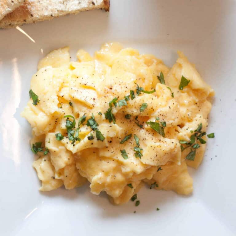 an overhead of a plate of soft scrambled eggs with basil.