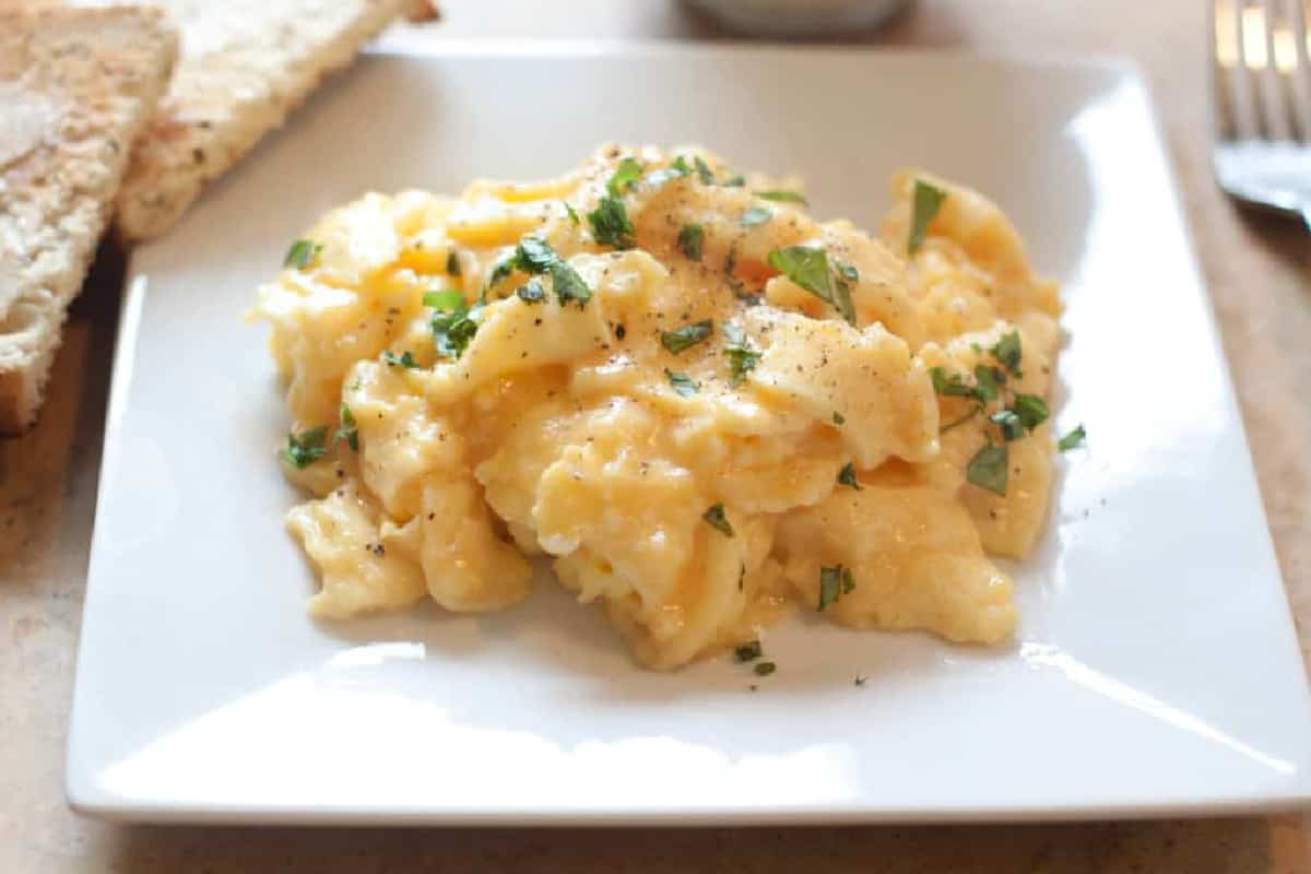 a plate of scrambled eggs topped with basil.