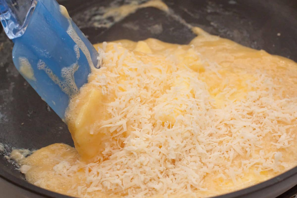 eggs in a pan with cheese and a spatula.