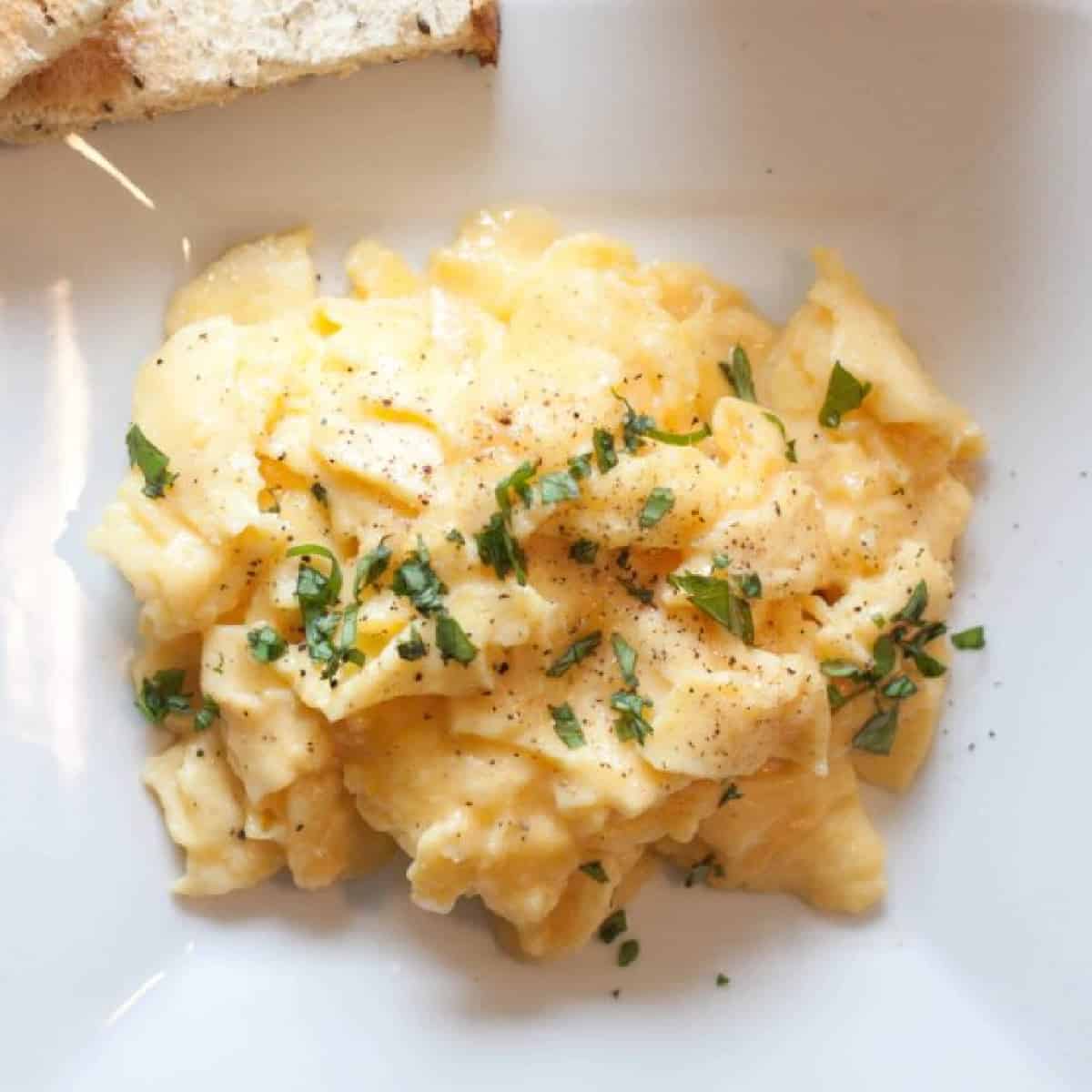 a plate of scrambled eggs topped with basil.
