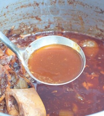 a ladle of beef stock over a pot