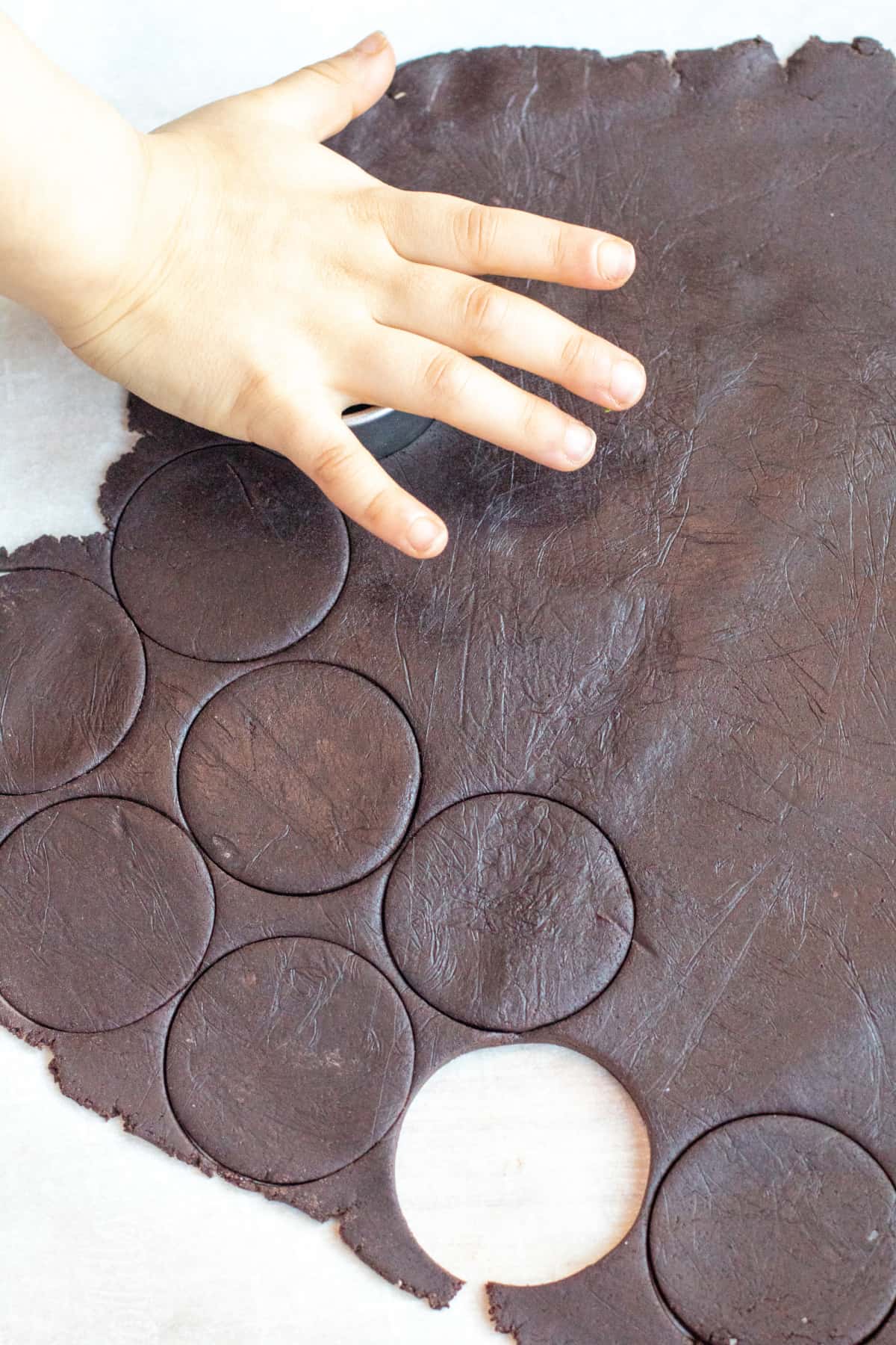 a little hand cutting circles out of a rolled our chocolate dough.