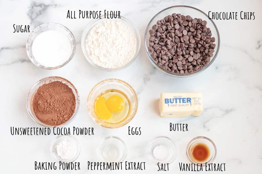 sugar, flour, chocolate chips, cocoa powder, eggs, butter, baking powder, extracts, salt on a counter.