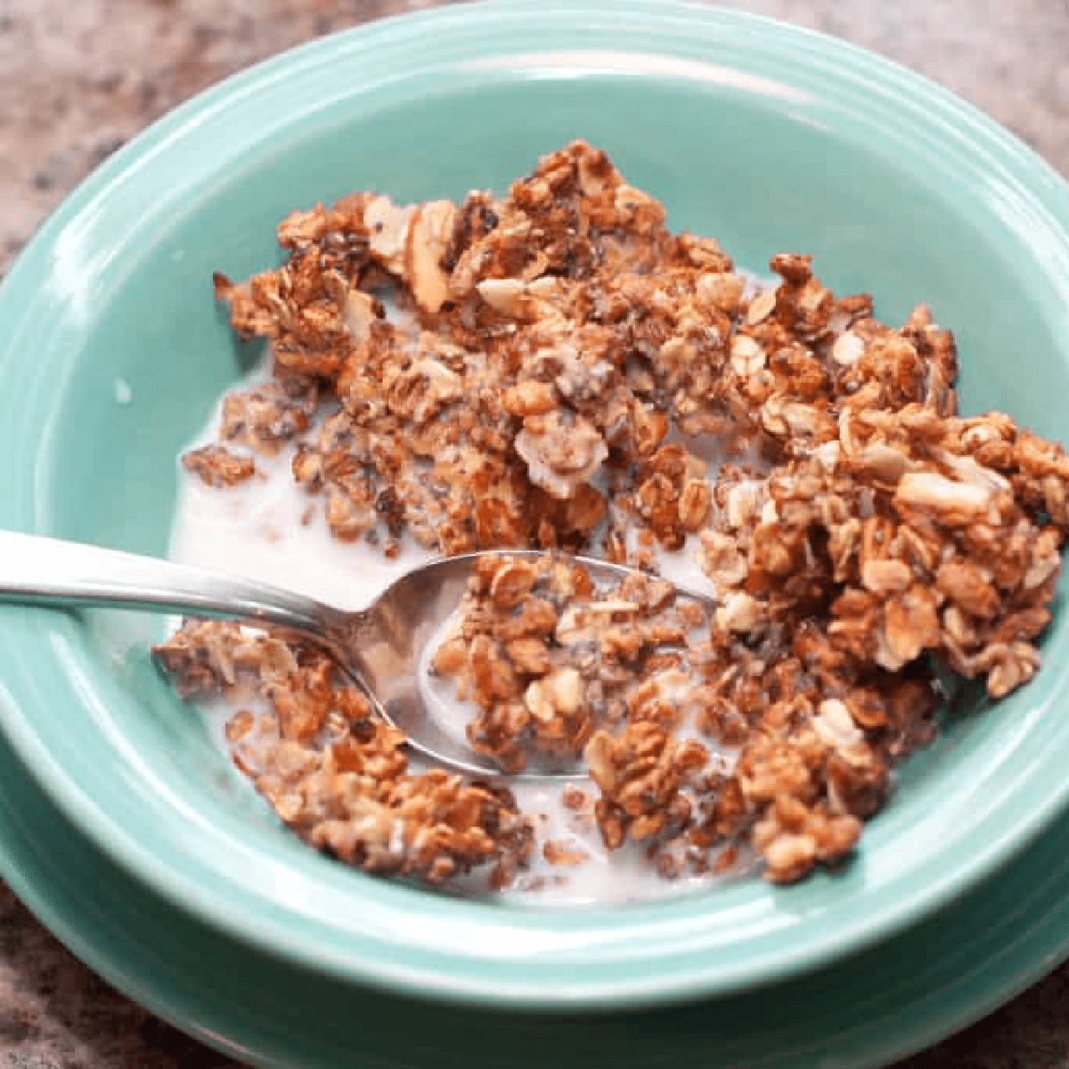 a bowl of cereal with milk and a spoon.